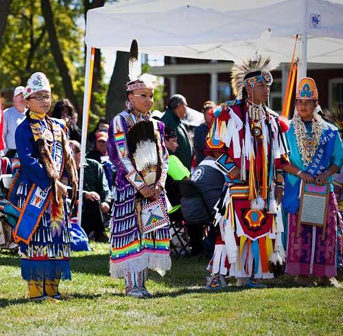 Four traditional dancers stand at attention